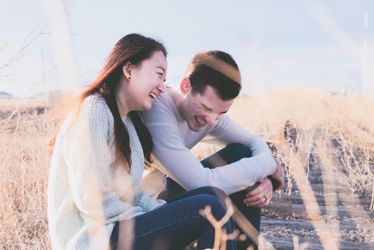 A husband and wife laughing together outdoors, the kind of easy moment a custom song can capture