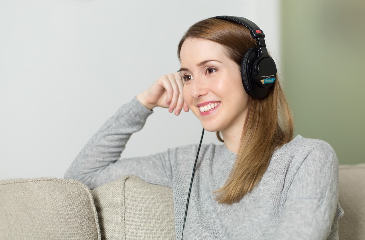 A woman wearing headphones with her eyes closed, listening to a personalized song made just for her