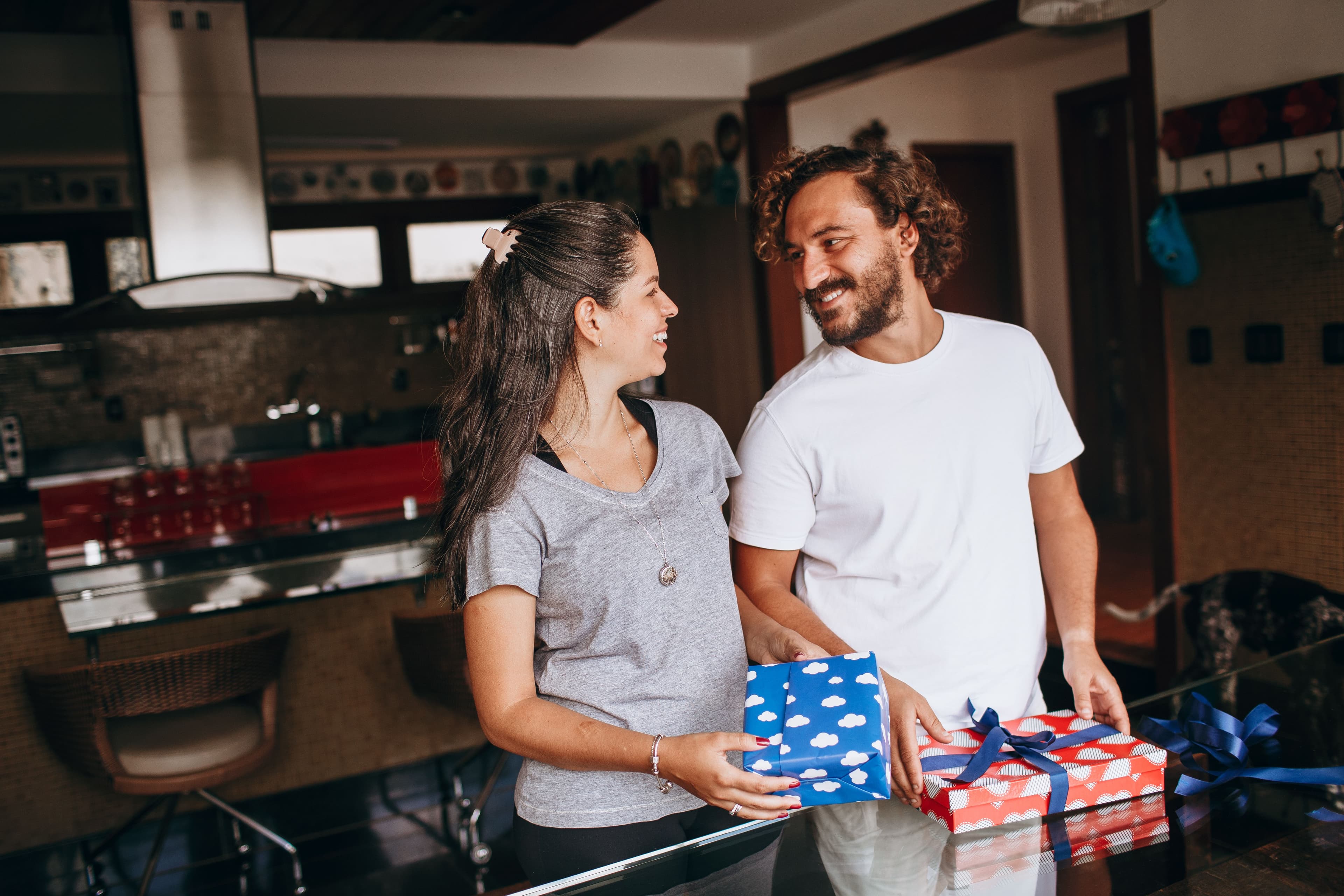 A smiling couple exchanging gifts together in a bright kitchen