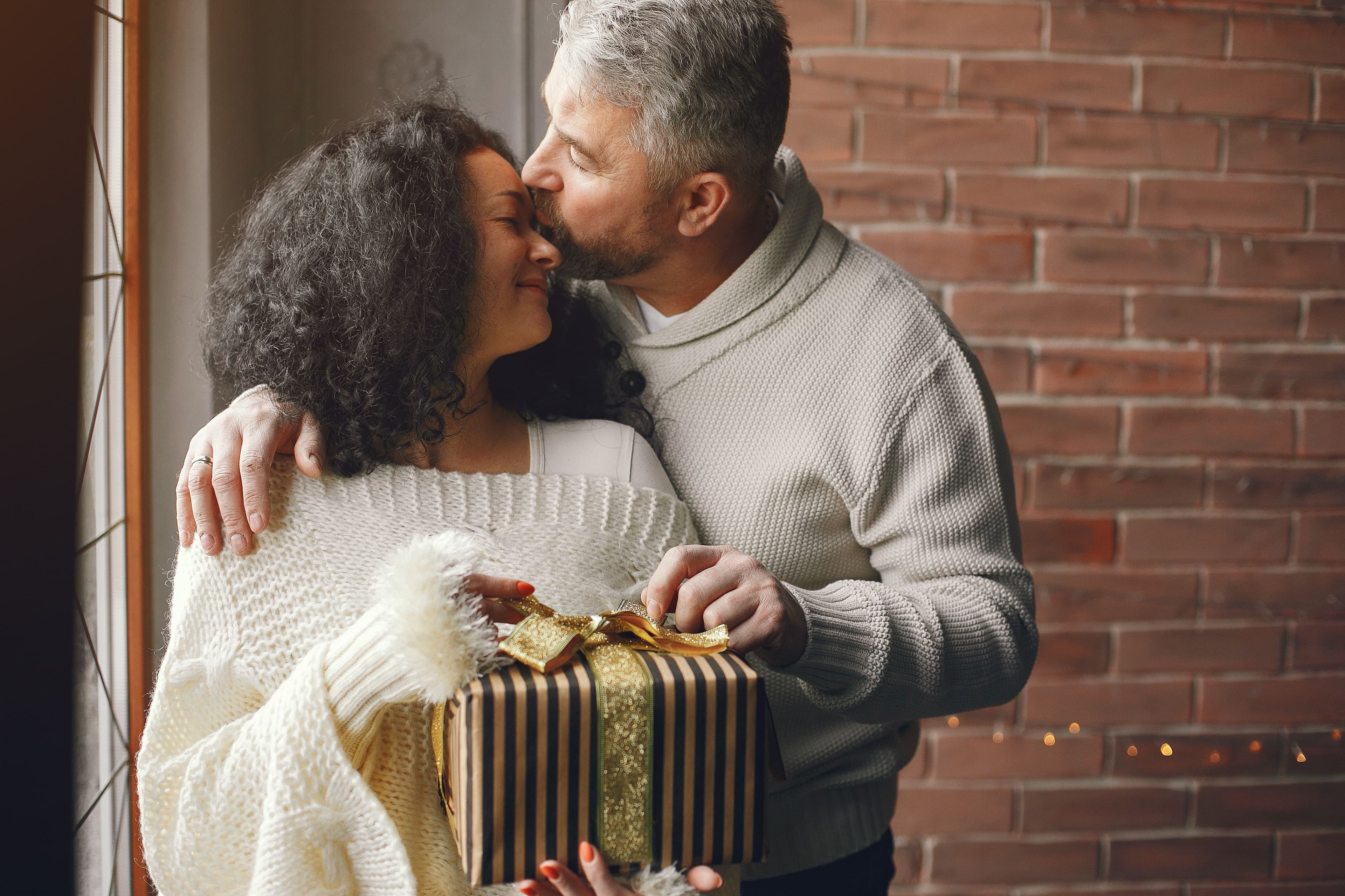 A couple sharing a warm moment while exchanging a gift indoors